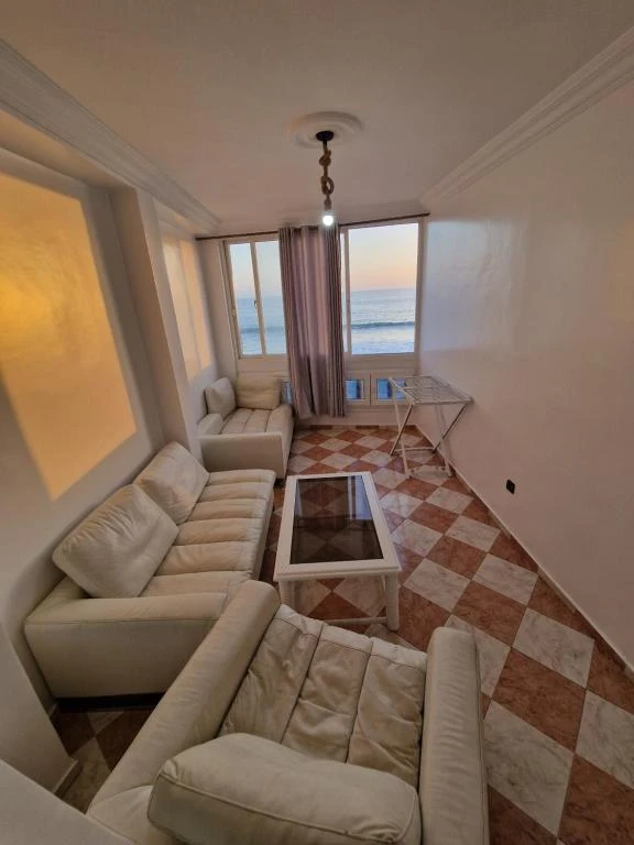 A modern apartment interior with a kitchenette and living area with an ocean view.